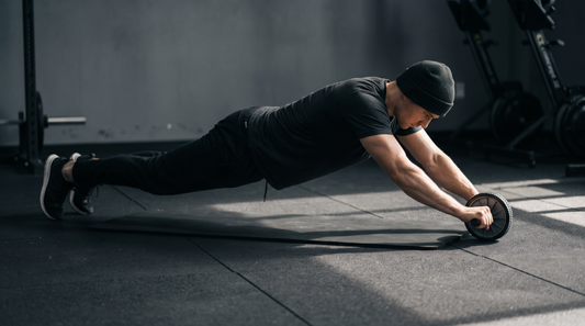 A lifter at full extension on an ab roller wheel with knees on a mat