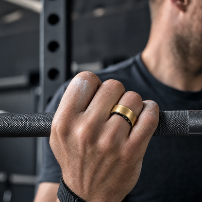 Gold smart ring worn on a hand gripping a barbell