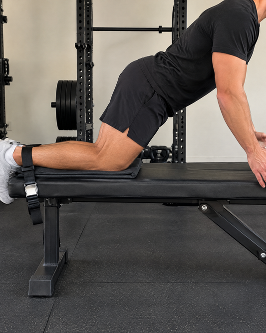 Athlete doing a Nordic hamstring curl with ankles strapped to a flat bench