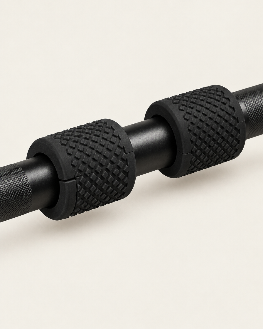 Pair of black fat grips clamped on a barbell showing the split that slides over the bar