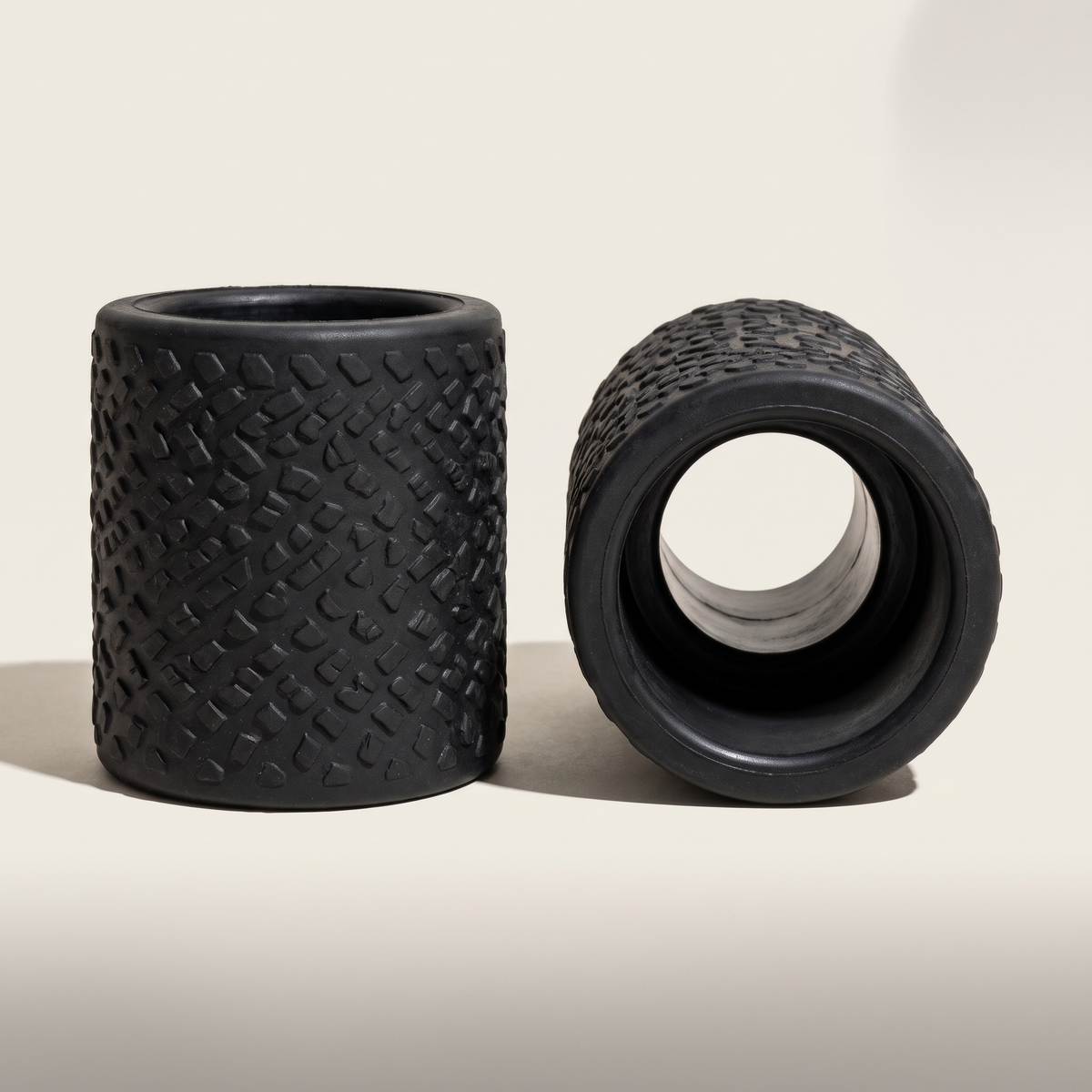 Pair of fat grips on a bone background, one open showing the bar cavity