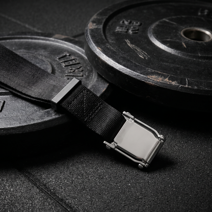 Nordic curl strap on a gym floor beside a weight plate